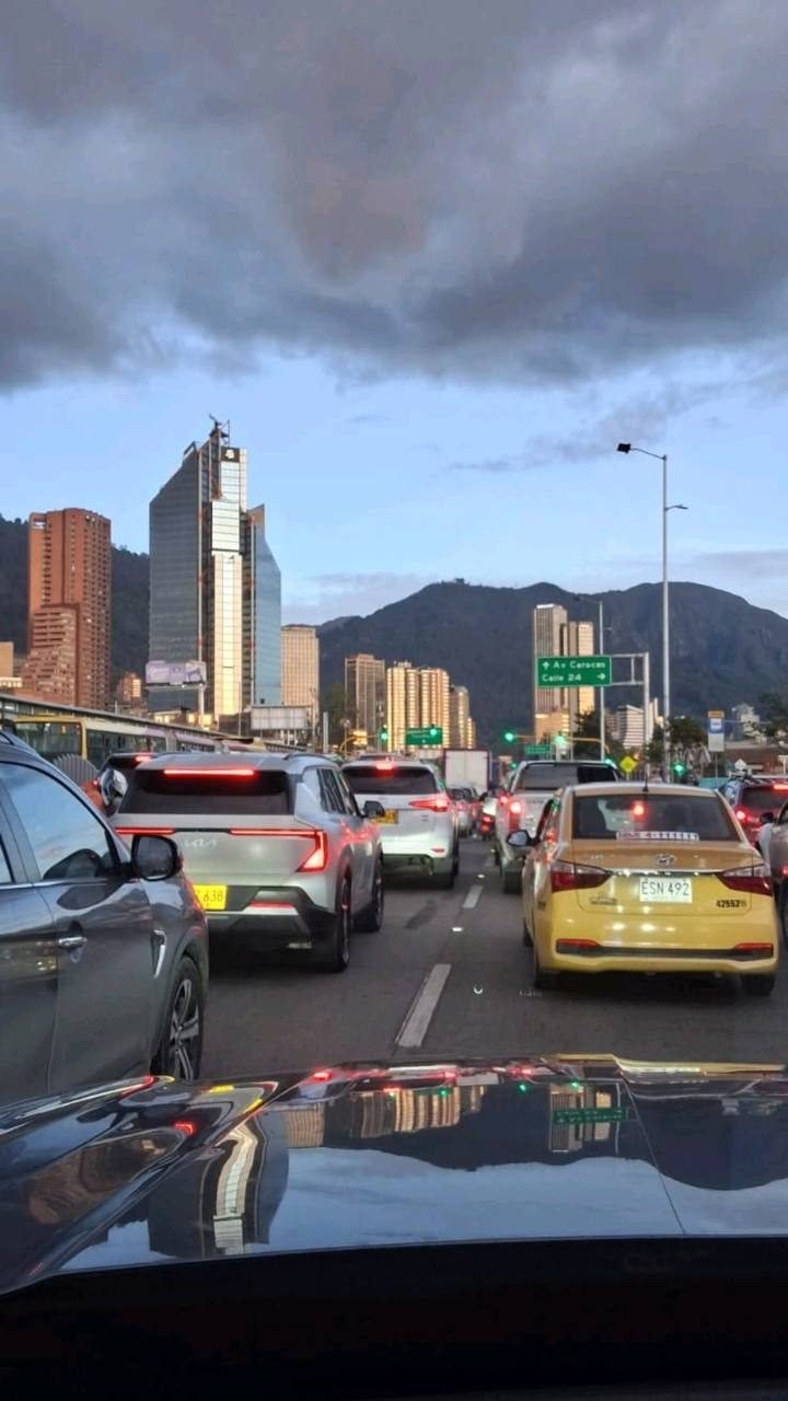 Vista del tráfico desde el interior de un carro, con edificios y montañas al fondo